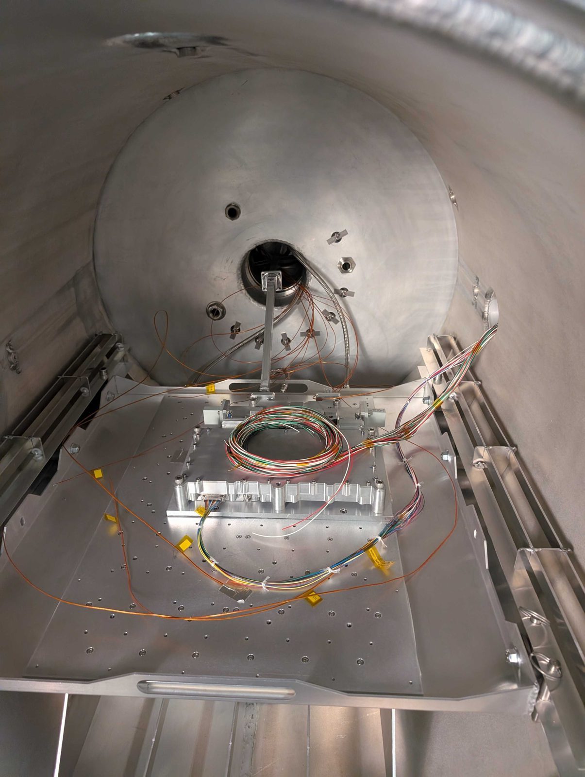 Machined high-power amplifier housing wired with thermocouples inside a thermal vacuum chamber